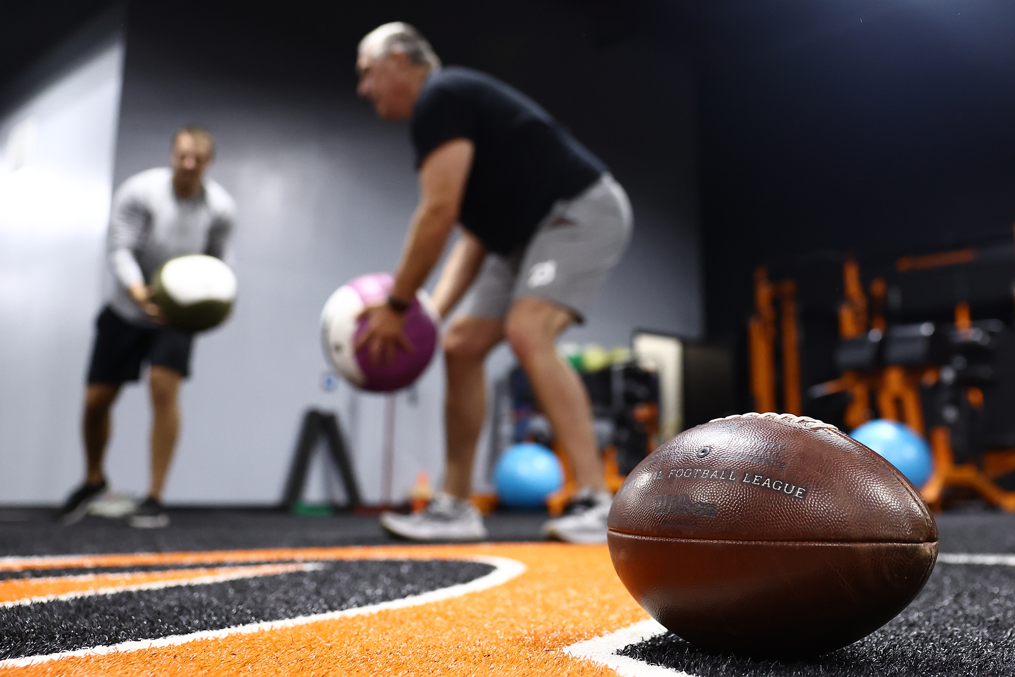 Former pros do medicine ball work with a football in focus