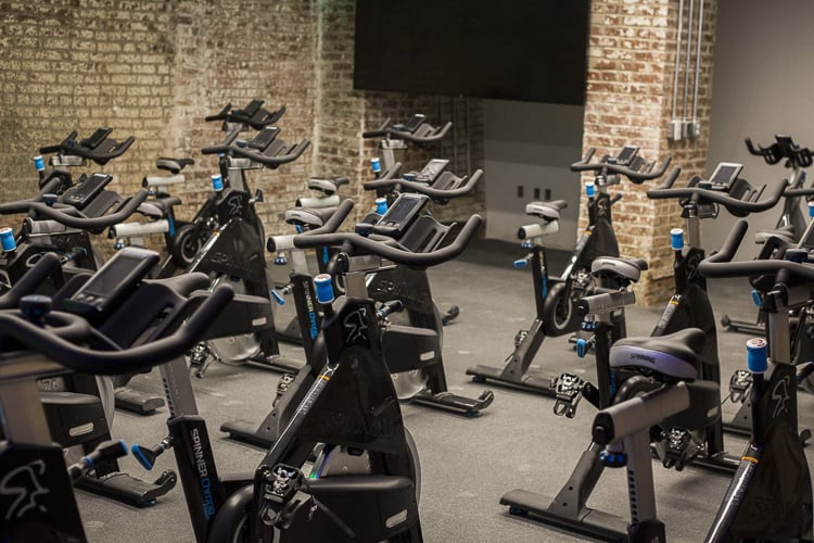 Indoor cycling studio with multiple stationary bikes and exposed brick walls.