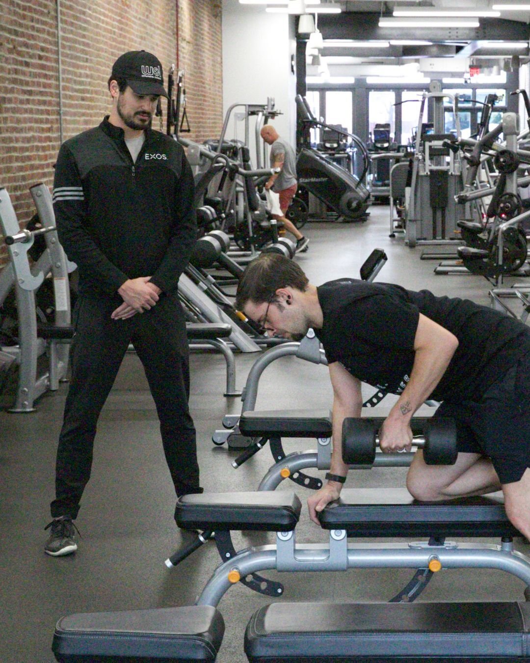 An Exos coach supports an employee through exercises to return to full work capacity and beyond.