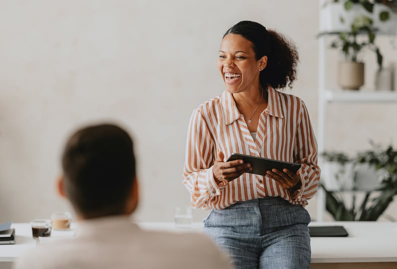 A smiling coach leads a workplace session, demonstrating how Exos coaching builds confident, resilient leaders.