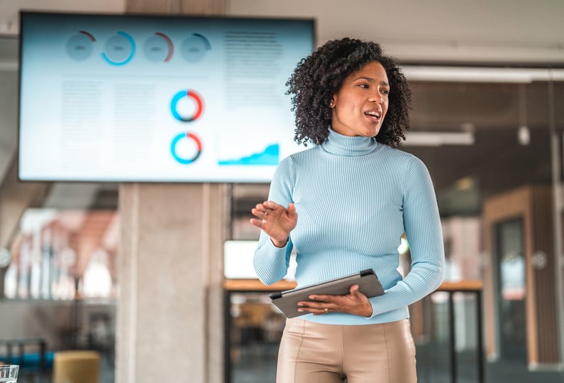 Leader presenting with confidence during a workplace meeting, modeling agency and intentional leadership.