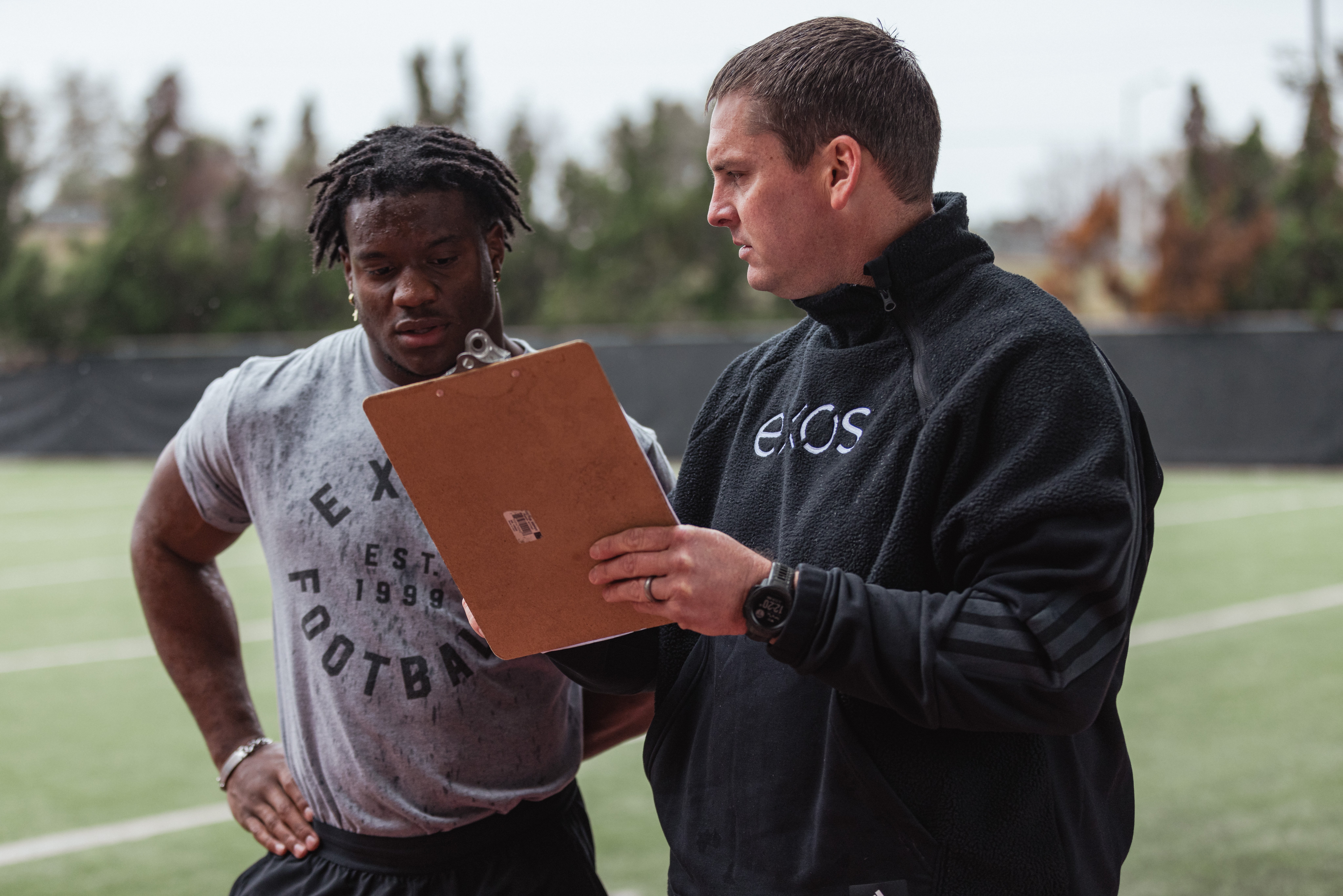 Kenneth Walker talking to his Exos coach, strategizing on technique to beat his forty-yard dash record.