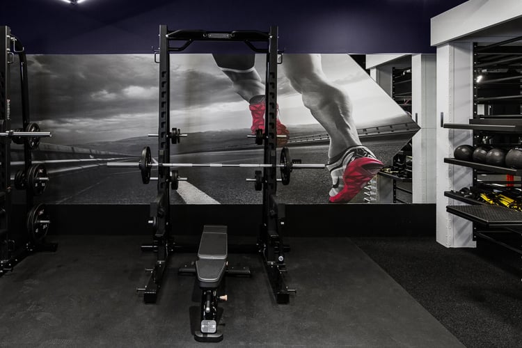 Strength zone featuring a squat rack and graphic wall art, designed to inspire movement and support heavy training.