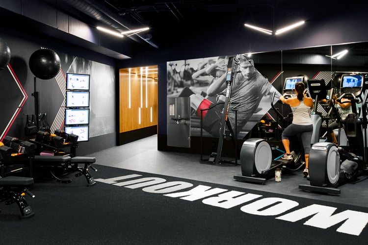 Cardio and strength zone featuring digital displays, mural graphics, and equipment designed to support guided training sessions.