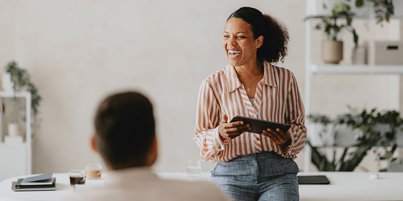 A smiling coach leads a workplace session, demonstrating how Exos coaching builds confident, resilient leaders.