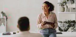 A smiling coach leads a workplace session, demonstrating how Exos coaching builds confident, resilient leaders.