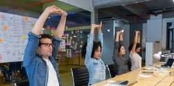 A room full of employees stretching at a meeting desk