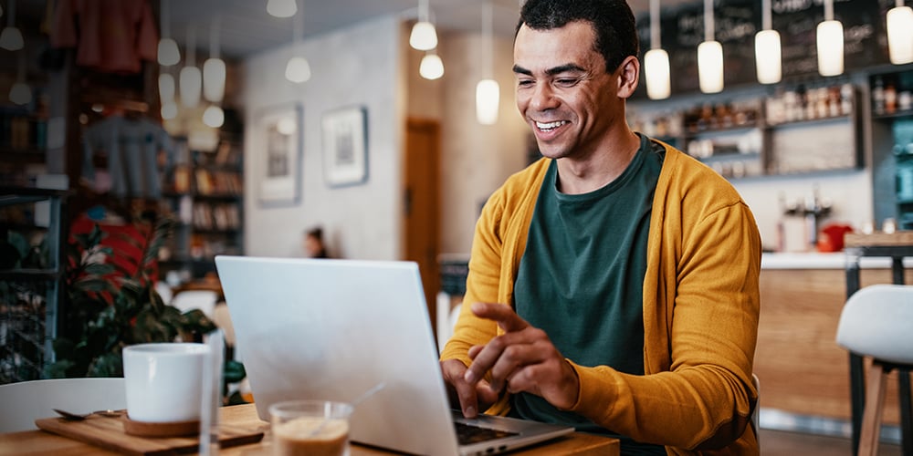 Man smiling in a cafe while on a remote work call.