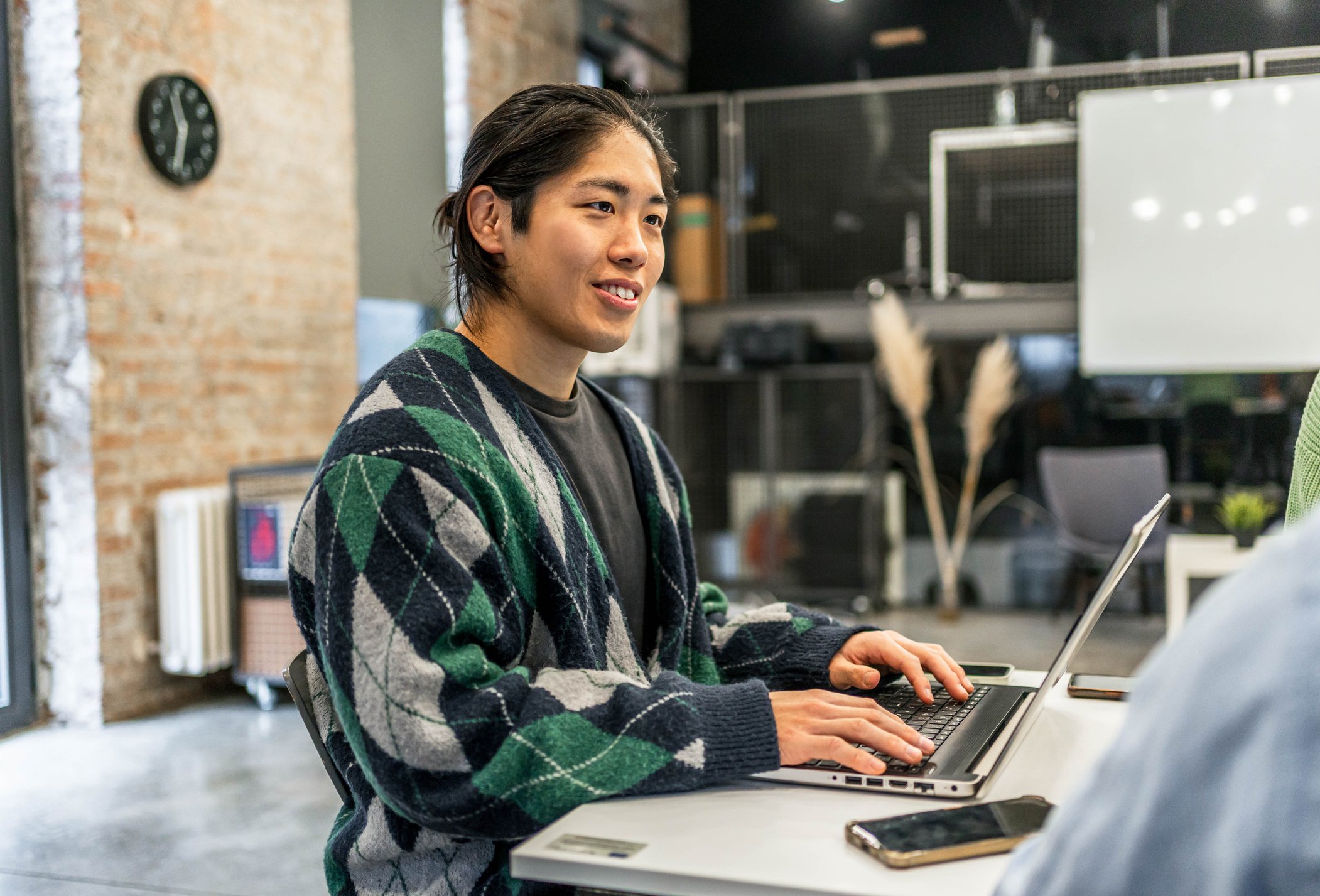Focused man smiling while typing on laptop, fully engaged in his work.