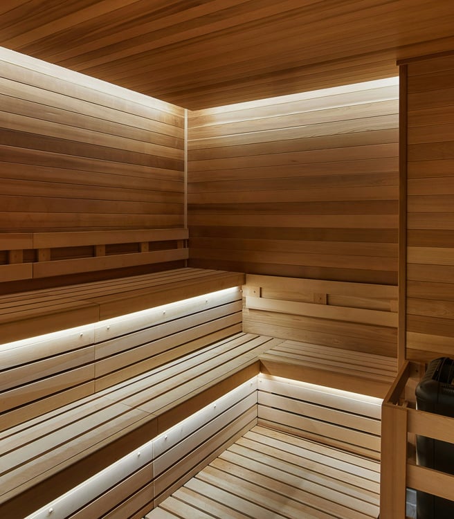 Wood-paneled sauna with tiered seating and soft LED lighting along the benches.