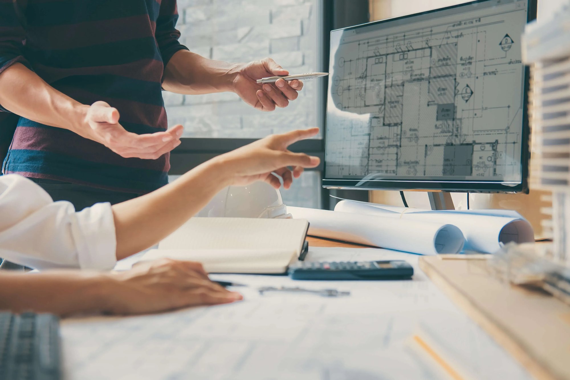 Team reviewing architectural plans on screen for workplace space allocation.