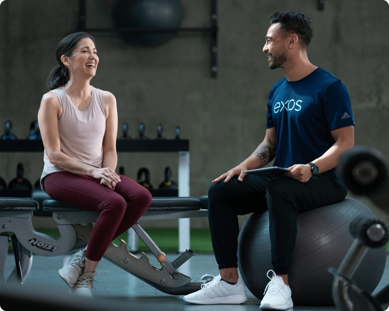 A woman speaks to an Exos coach about her custom Gameplan.