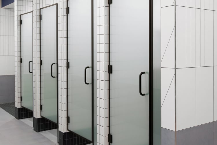 Row of private frosted-glass shower stalls in a clean, modern locker room designed for comfort and privacy.