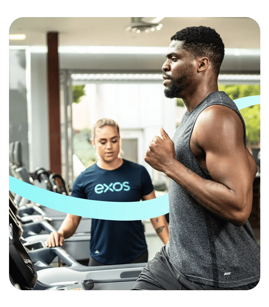 Exos coach guiding an employee through personalized treadmill training in a well-being facility.