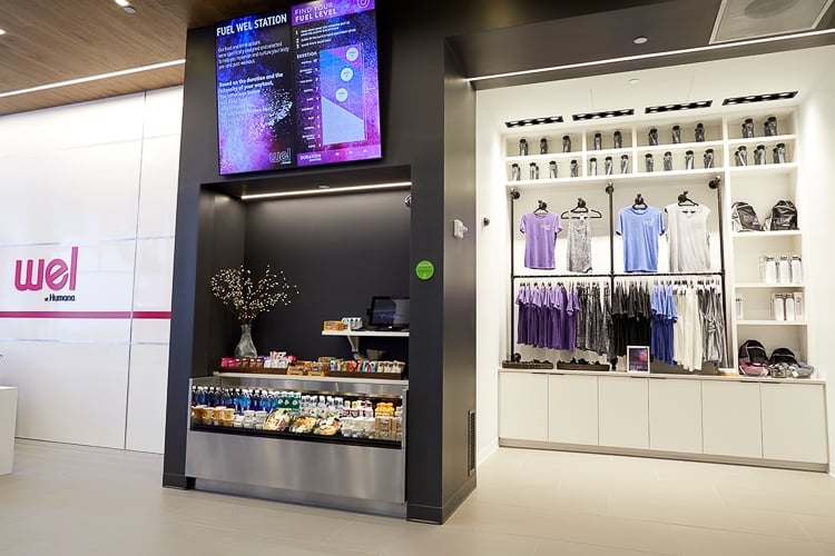 Wellness retail area with workout apparel, water bottles, and a healthy grab-and-go snack station.