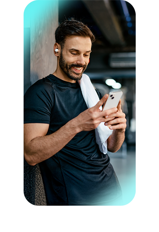 Man in a fitness center looking at his phone, receiving guided support from his Exos coach.