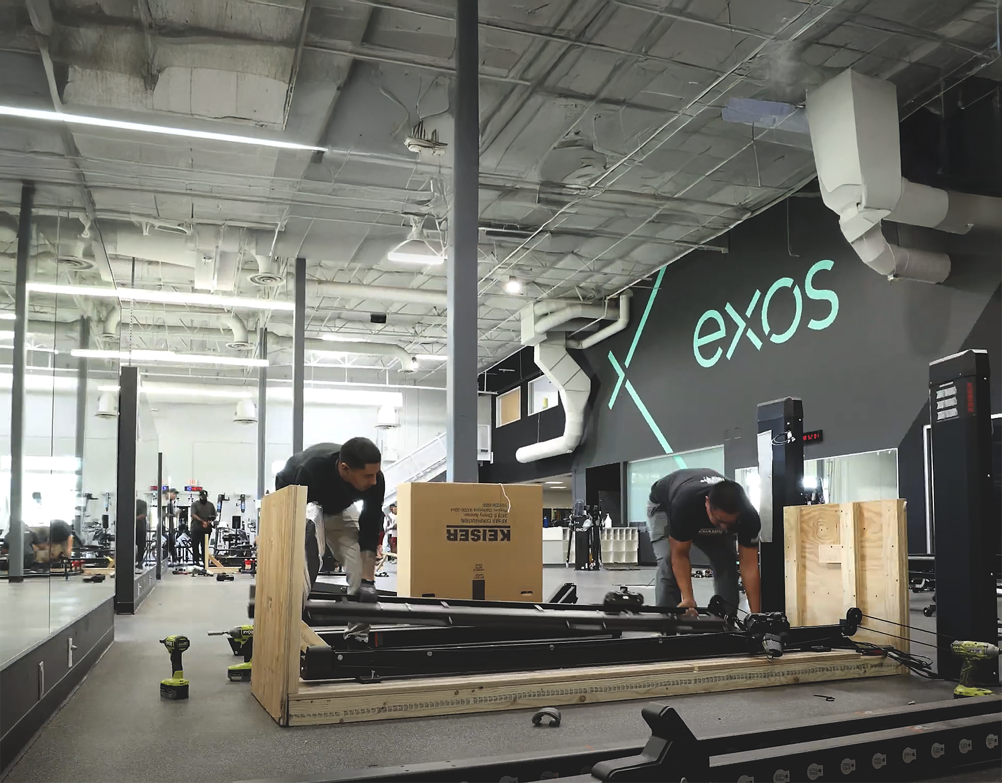 Team unpacking and installing fitness equipment inside an Exos-designed performance facility.