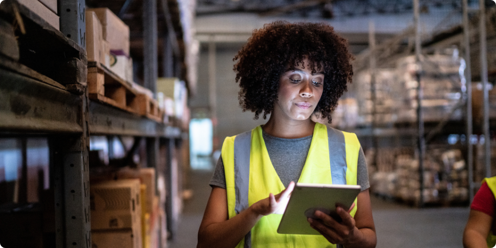 Employee using a tablet to manage tasks and stay engaged while working in a warehouse aisle