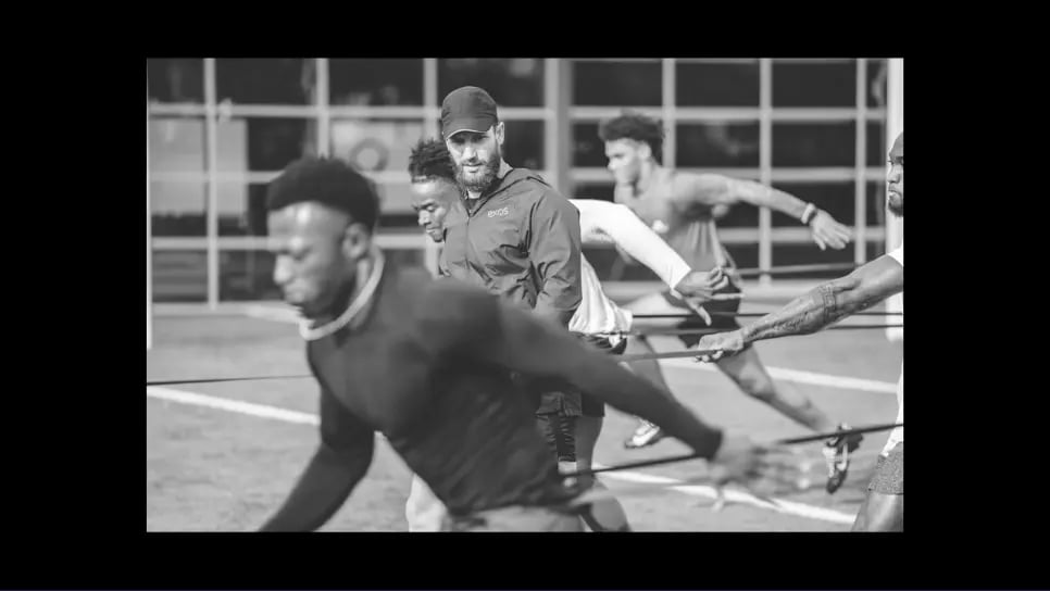Freeze frame from the video, men and a coach training for football.