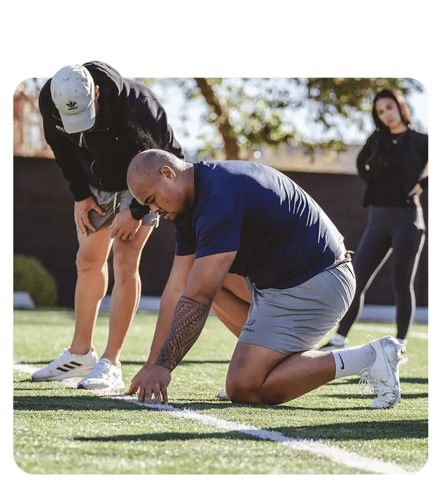 A man gets ready for his workout, assisted by Exos coaches in a field.