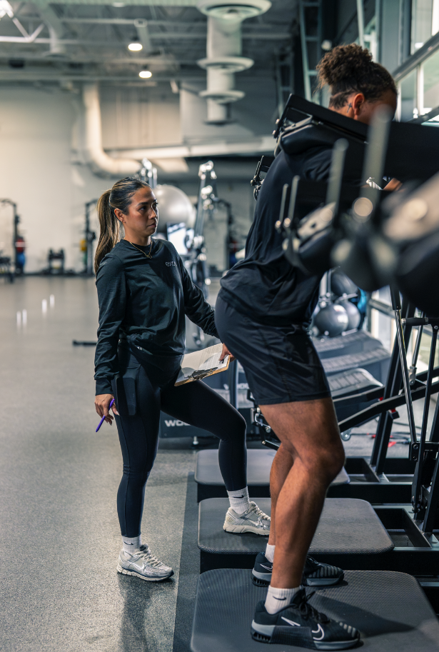 Exos coach watching an athlete perform a leg workout