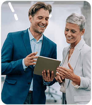 A man and woman review notes while smiling in a well-lit professional environment.