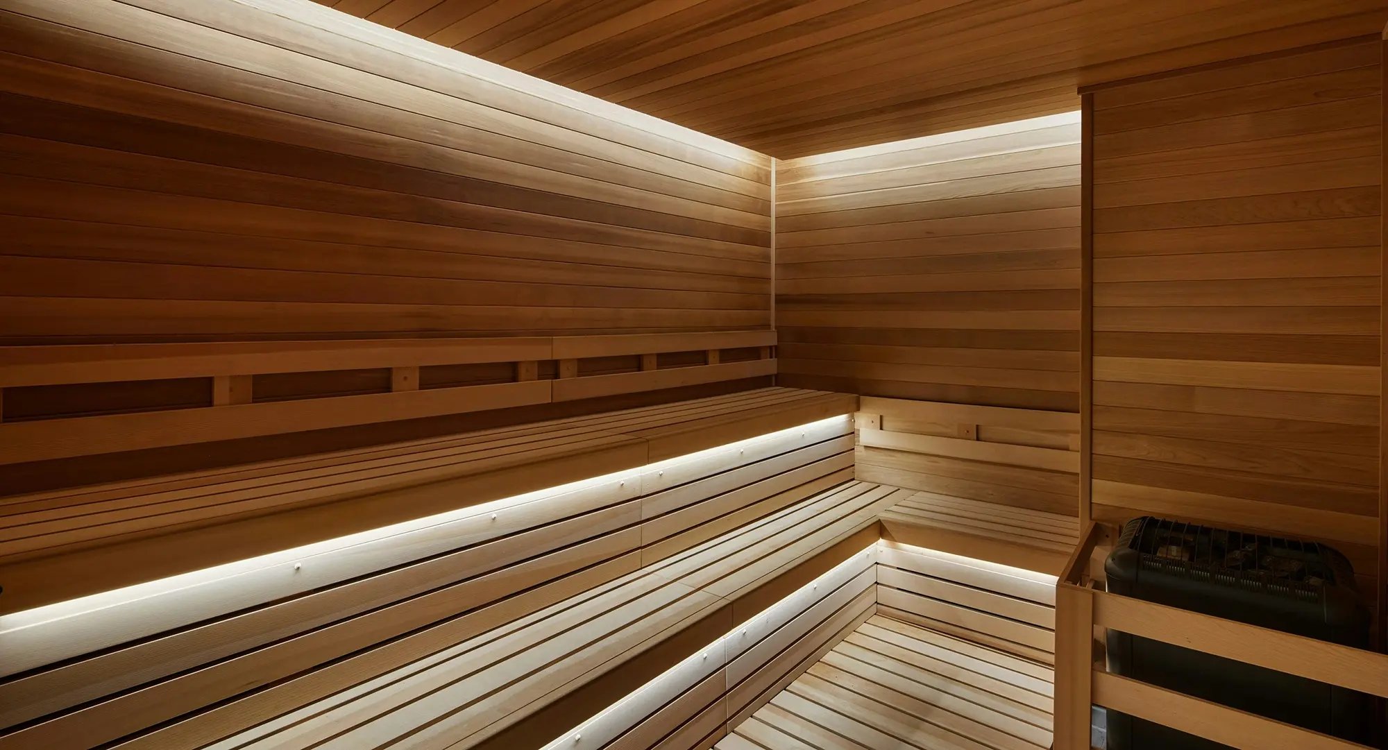 Wood-paneled sauna with tiered seating and soft LED lighting along the benches.
