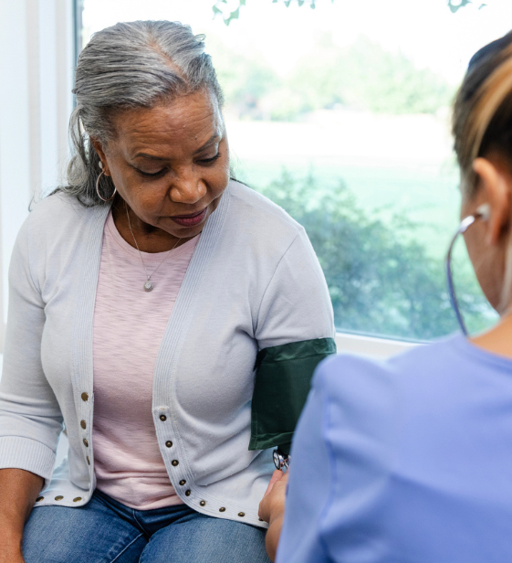 Healthcare professional checking woman’s blood pressure as part of employee wellness and chronic disease prevention.